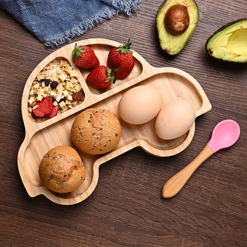 Wooden tray with compartments containing eggs, bread, and strawberries on a wooden surface.