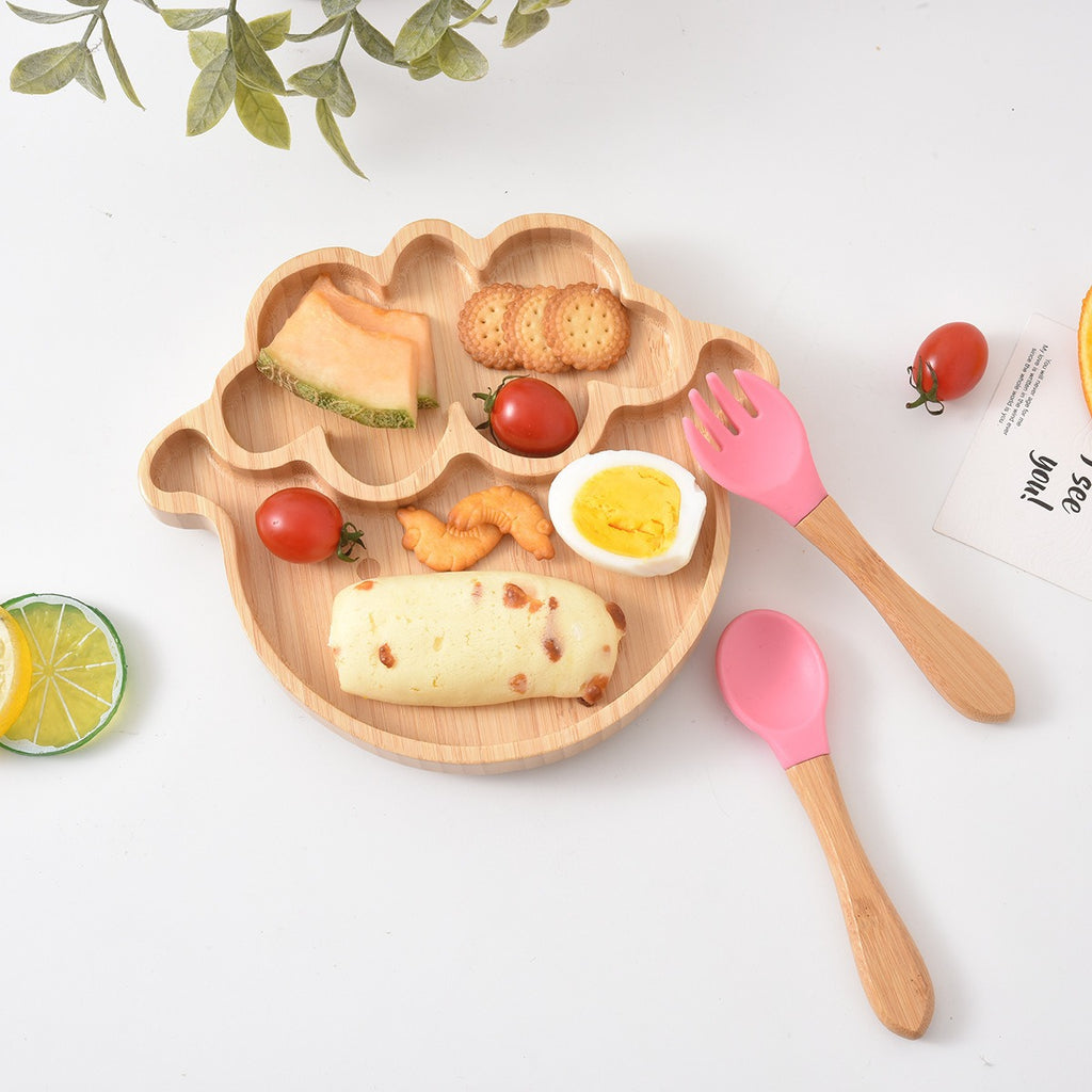 Wooden plate with food and pink utensils on a white surface