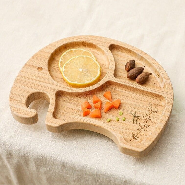 Wooden elephant-shaped tray with sliced lemon, carrots, and almonds on a beige surface